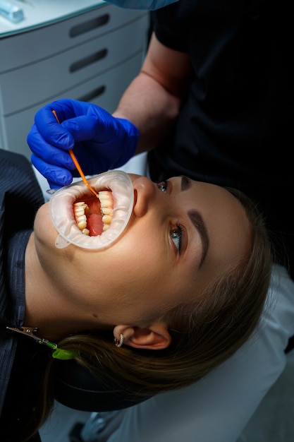 歯科矯正医は患者の歯に金属製のブレースを付けます。歯科矯正歯科治療。高品質の写真