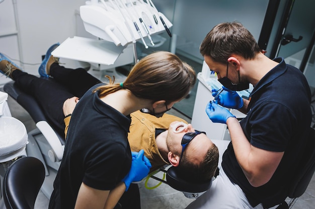 Photo an orthodontist treats the teeth of his patient in a modern bright office orthodontic treatment of teeth