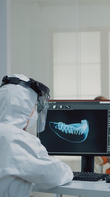 Orthodontisten analyseren virtuele tandenanimatie aan de balie van de orale kliniek. professionele assistent kijkt naar scan op computermonitor terwijl tandarts model voor patiëntimplantaat onderzoekt