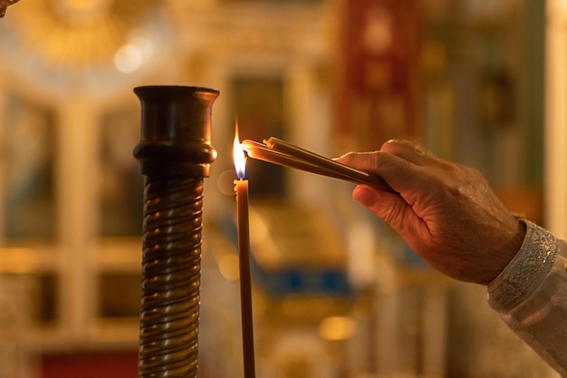 Orthodox church christianity hand of priest lighting burning candles in traditional orthodox church