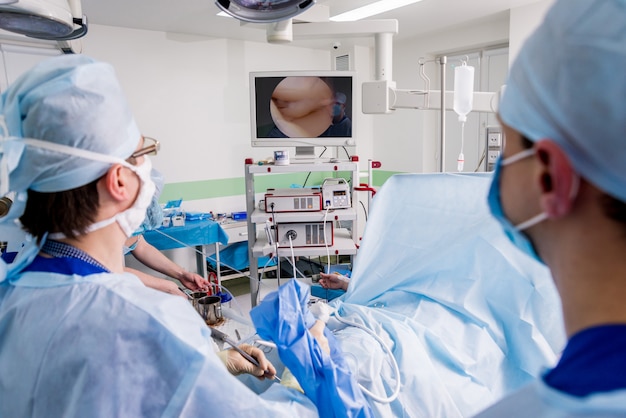 Orthopedic surgeons in teamwork in the operating room with modern arthroscopic tools.