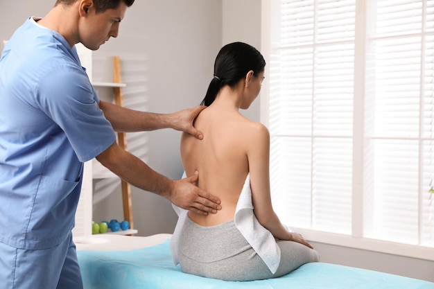 Photo orthopedist examining woman's back in clinic scoliosis treatment