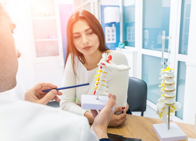 Orthopedist showing spine model to patient in hospital