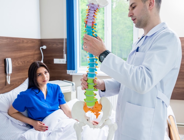 Orthopedist showing spine model to patient in hospital