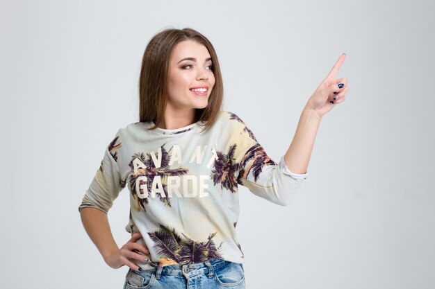 ortrait of a smiling casual woman touching invisible screen isolated on a white background