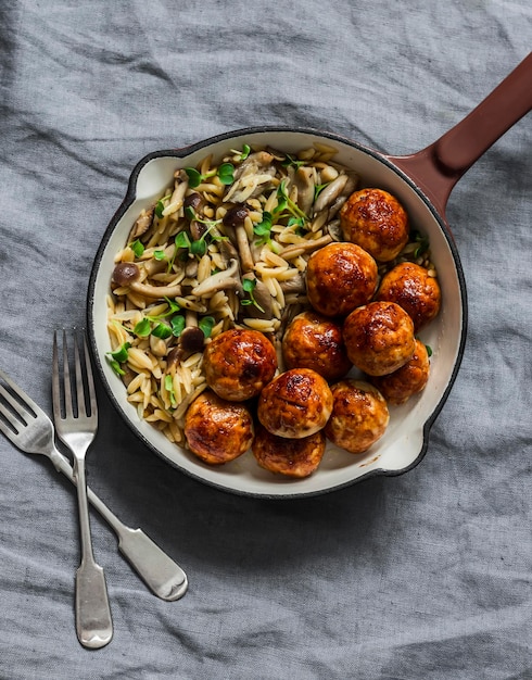 Orzo champignons pasta met teriyaki saus kip gebakken gehaktballen in een pan op een grijze achtergrond bovenaanzicht