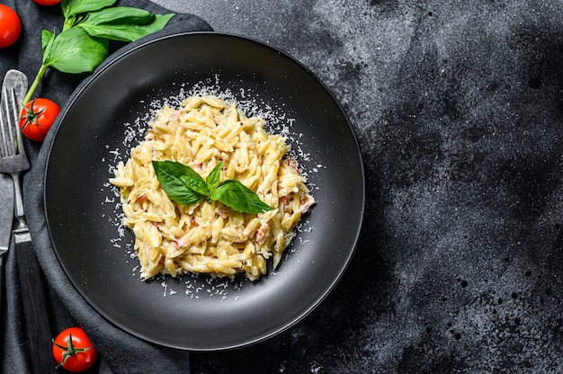 Orzo pasta with cream sauce, bacon and Basil. Prepared risoni. 