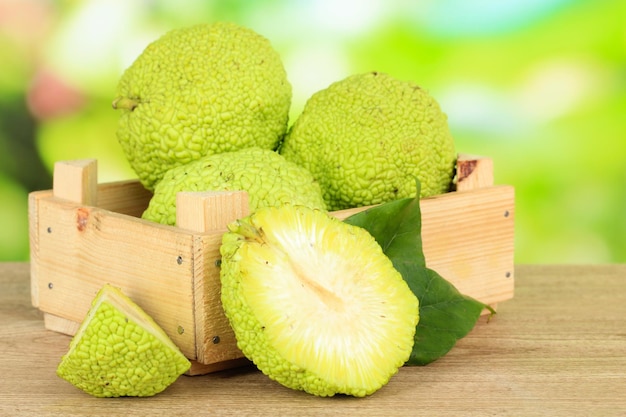 Osage Orange fruits Maclura pomifera in crate on wooden table on nature background