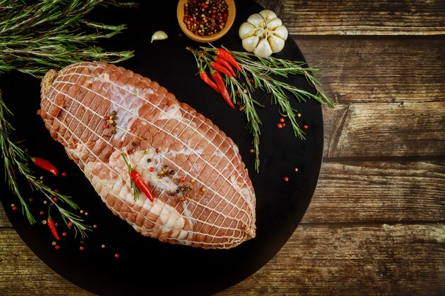 Ossenhaas van varkensvlees klaar voor roosteren met kruiden op een zwarte bord