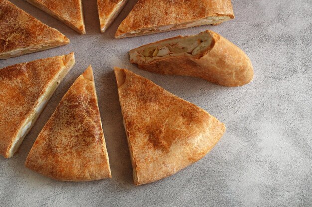 Ossetian round cake with filling cut into pieces on a gray background