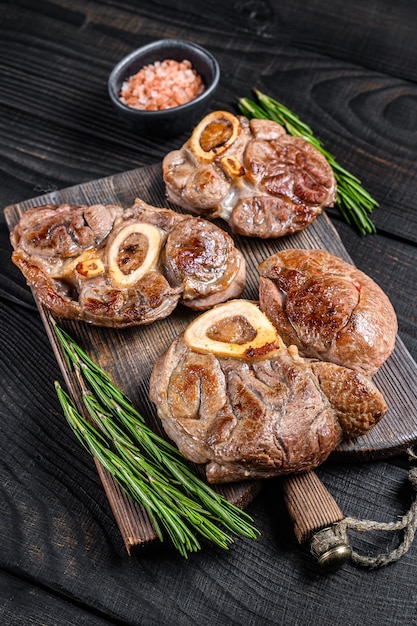 Osso buco cooked Veal shank steak,  italian ossobuco. Black wooden background. Top view.