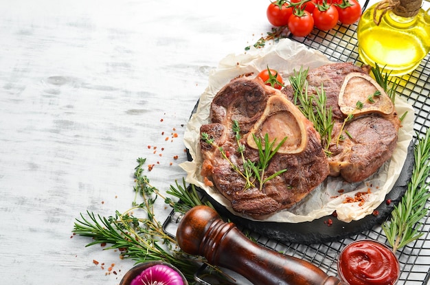 Osso buco gekookte kalfsschenkel met kruiden en groenten op een witte houten ondergrond Plat lag Bovenaanzicht