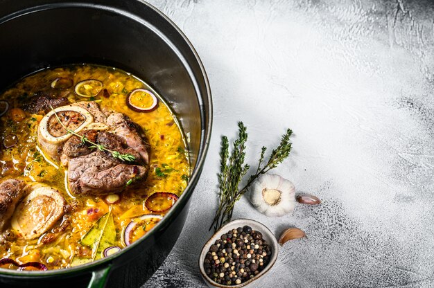 Ossobuco vleesstoofpotje met groenten. Osso buco. Grijze achtergrond.