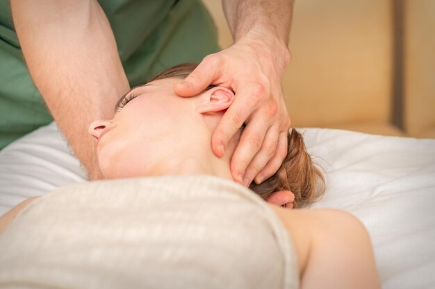 Osteopaat die massage op het vrouwelijke hoofd doet in het centrum van de revalidatiekliniek.