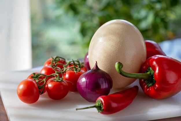 Photo ostrich egg farm organic vegetables tomatoes paprika onion chili ingredients for making an omelet shakshuka soft selective focus