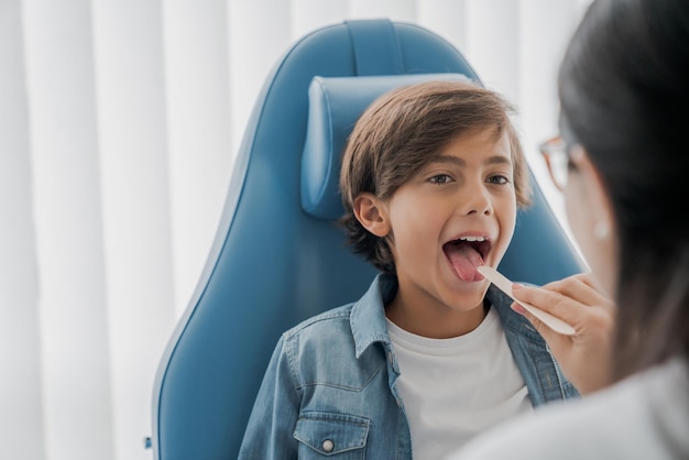 Otolaryngologist examines boy's throat