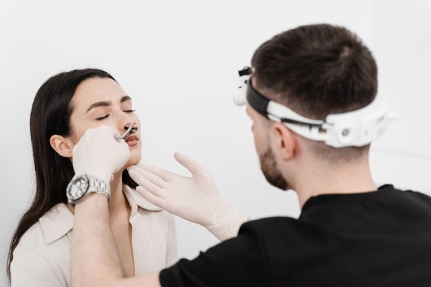 Otolaryngologist examines girl nose before procedure of endoscopy of nose Consultation with ENT doctor Rhinoscopy of woman nose