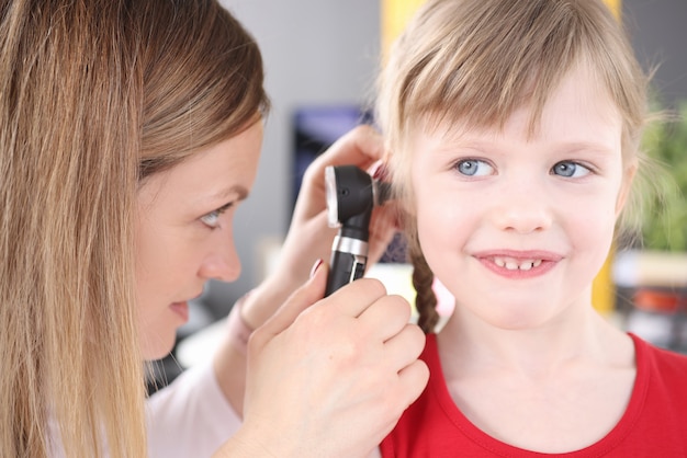 Otorhinolaryngologist conducts medical examination of little girl ear ear disease in childhood