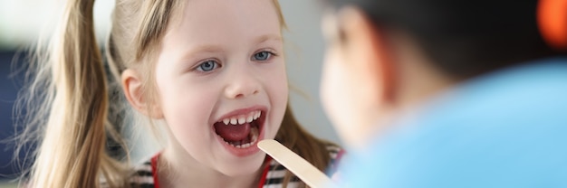 Photo otorhinolaryngologist doctor examining sore throat little girl in clinic