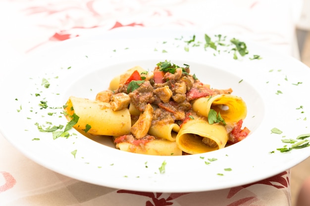 Otranto stad, regio Puglia, Zuid-Italië. Traditionele Paccheri-pasta met zwaardvis, geserveerd met tomaat, peterselie, olijfolie. Daglicht, echt restaurant in Otranto.