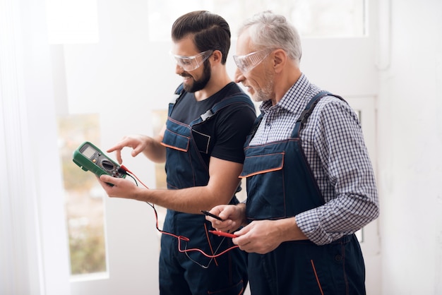 Oud en de jonge kerel zien samen digitale multimeter.