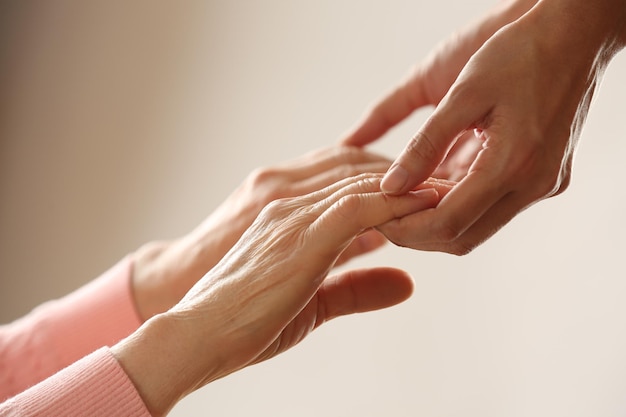 Foto oud en jong hand in hand op lichte achtergrond close-up