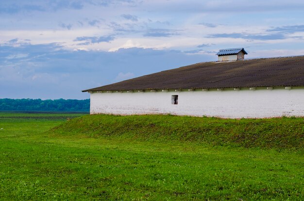 Oud gebouw onder lente groen veld onder een bewolkte hemel na de regen