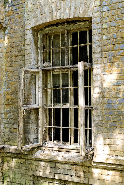 Oud gebroken raam in een bakstenen huis