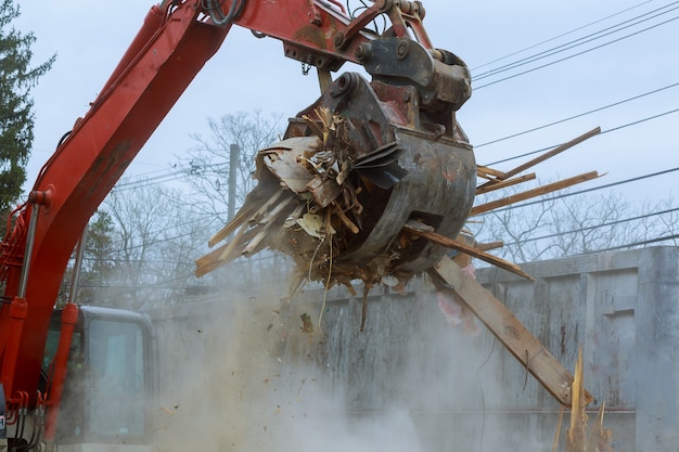 Oud huis dat door een grote backhoe wordt gesloopt