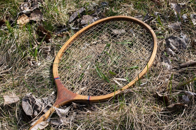 Oud kapot badmintonracket in het gras