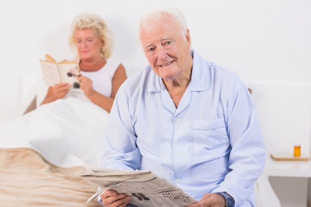 Oud paar dat camera bekijkt terwijl het lezen