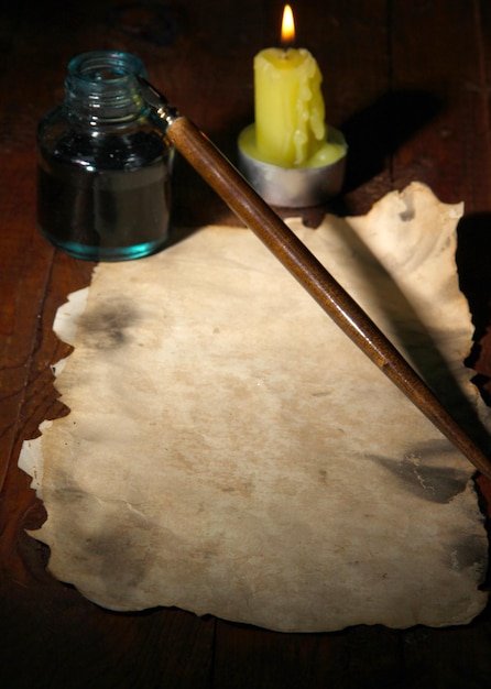 Oud papier met inktpen bij het aansteken van kaars op houten tafel