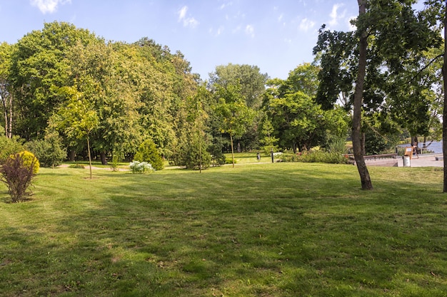 Oud park met groene gazons en grote bomen.