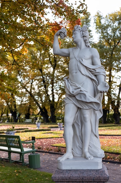 Oud parkstandbeeld van sensuele Griekse of Italiaanse Renaissance-tijdperkvrouw met bloemen in stadspark ging naar gouden herfstkleuren,