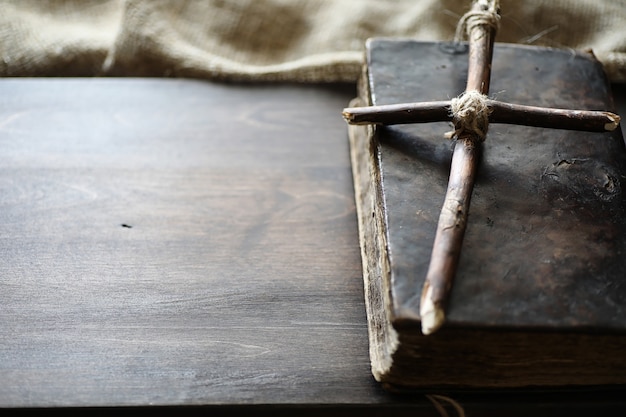 Oud religieus boek en houten kruis op de achtergrond van een houten en jute