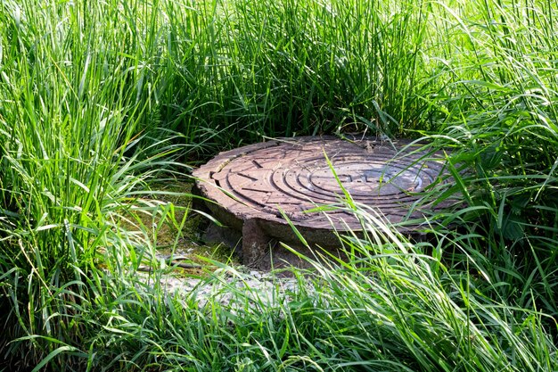 Oud rioolmangat tussen het groene gras