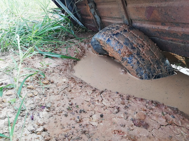 Oud rubberwiel in modderig gat op grondgrond