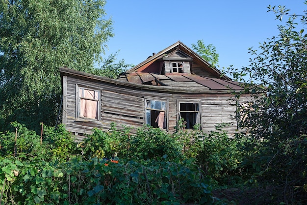 Oud verlaten rustiek houten huis is omgeven door het groen van de kersenboomgaard Landelijk gebied