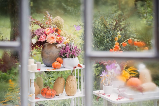 Oud wit houten raam met regendruppels en herfstdecor in de tuin