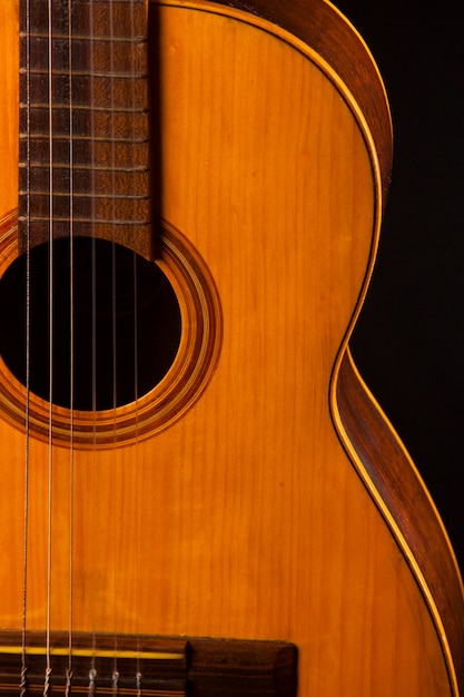 Oude akoestische gitaar op een zwarte muur.