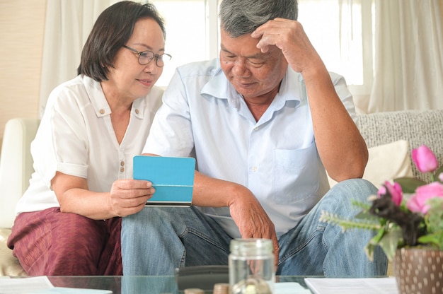 Oude Aziatische vrouwen en mannen zitten op de bank, zij maken financiële plannen.