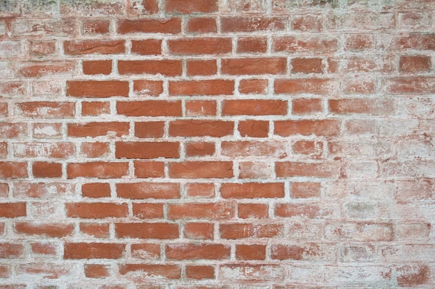 Oude bakstenen muur bedekt met resten van kalkpleister