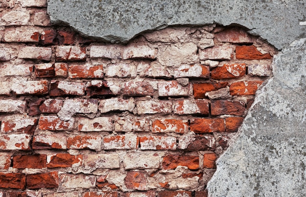 Oude bakstenen muur met gebarsten pleister