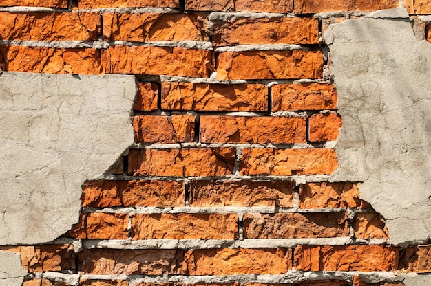 Oude bakstenen muur met gevallen gips Achtergrond van de textuur van de barstbakstenen muur