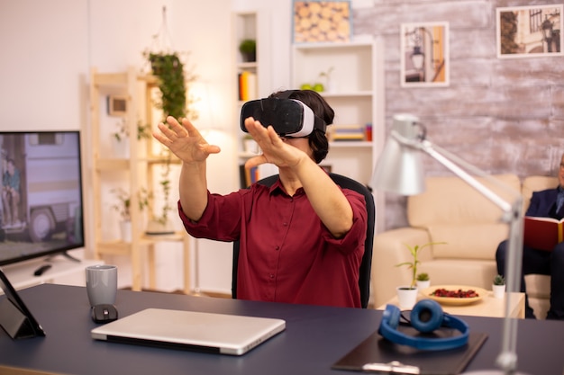 Oude bejaarde vrouw gebruikt voor het eerst een VR virtual reality-headset in haar huis. Concept van actieve ouderen die moderne technologie gebruiken