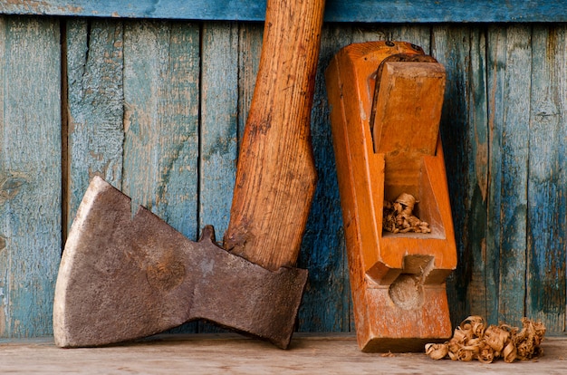 Oude bijl, schaafmachine en spaanders op een blauwe houten tafel