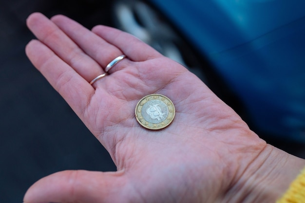 Oude Bitcoin-munt in de palm van je hand. een meisje houdt een versleten bitcoin-munt in haar hand.