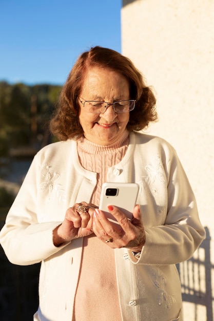 Oude blanke vrouw die lacht met behulp van een smartphone buitenshuis