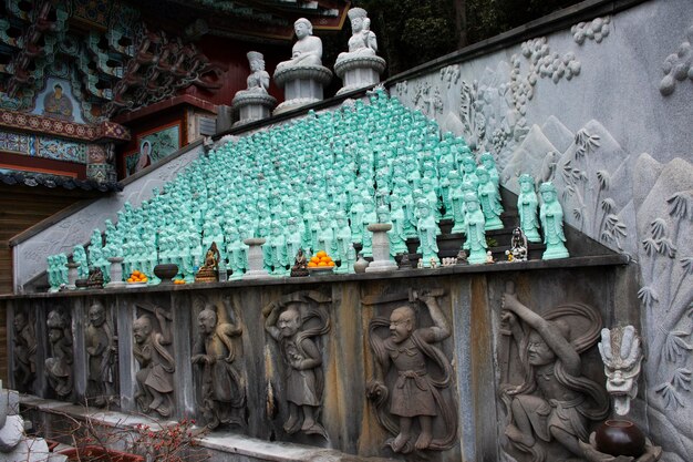 Oude boeddhabeeld en antieke kleine godheid engelfiguur voor Koreaanse mensen reizigers reizen bezoek en bidden zegen wens heilig mysterie in de Sanbangsa-tempel in de stad Seogwipo in Jeju, Zuid-Korea