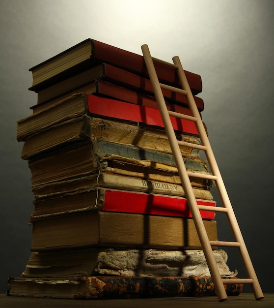 Foto oude boeken en houten ladder op grijze achtergrond